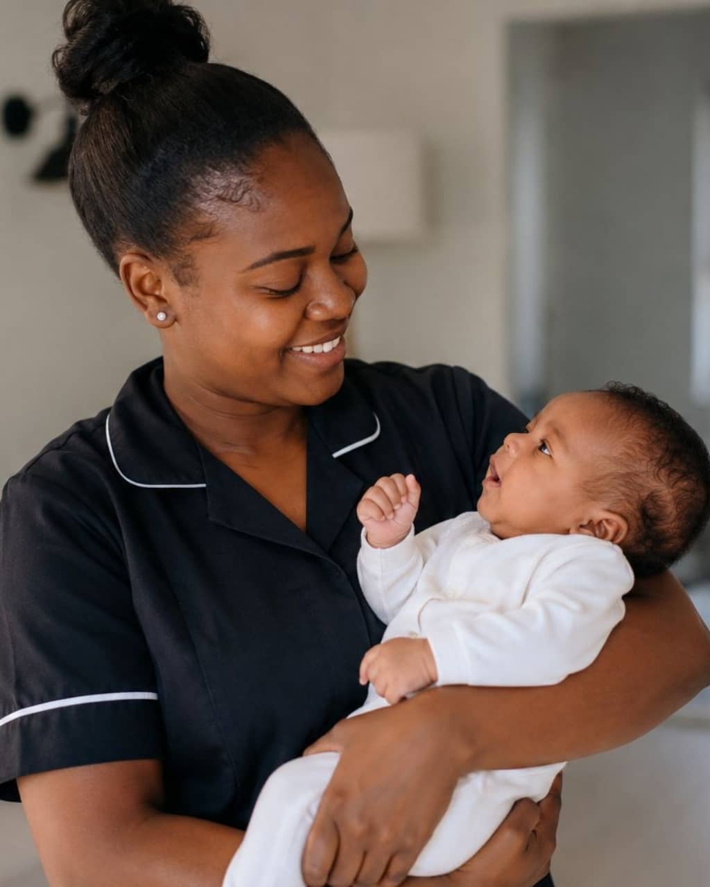 A caregiver smiling with a young child in a sunlit home
